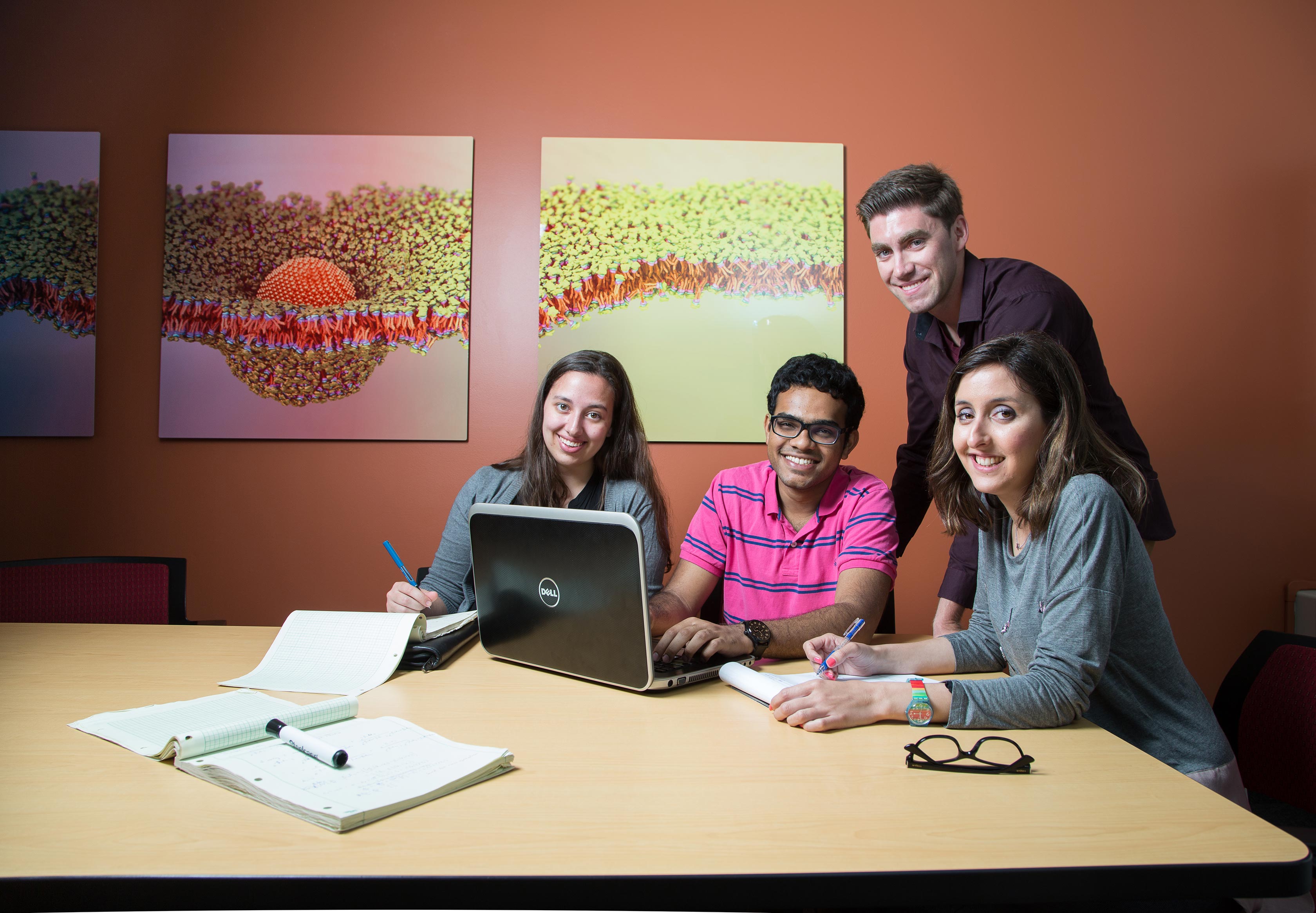 Engineering students working on a laptop around a desk