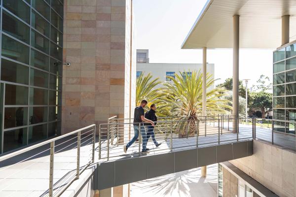 Two grad student walk on a bridge of a UCSB engineering building