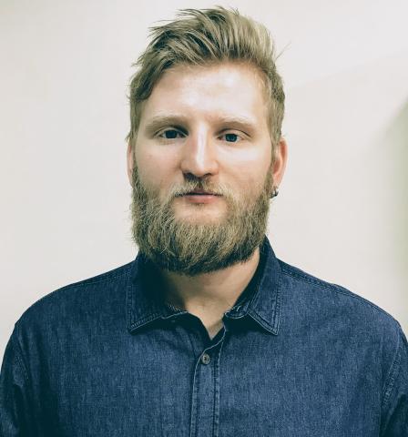 headshot of Arthur, wearing denim button up, smiling 