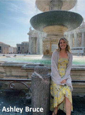 photo of Ashley, sitting in front of a fountain, wearing a yellow dress, smiling