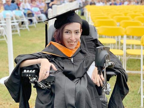 photo of Atieh, wearing a black graduation gown and hat, smiling