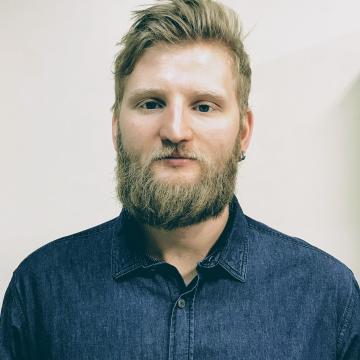 headshot of Arthur, wearing denim button up, smiling 