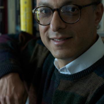 headshot of Khaled, smiling and wearing black rimmed glasses