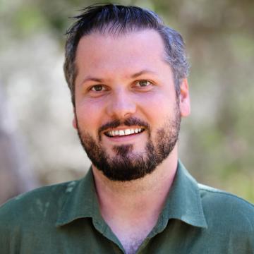 headshot of Michael, wearing green button up, smiling