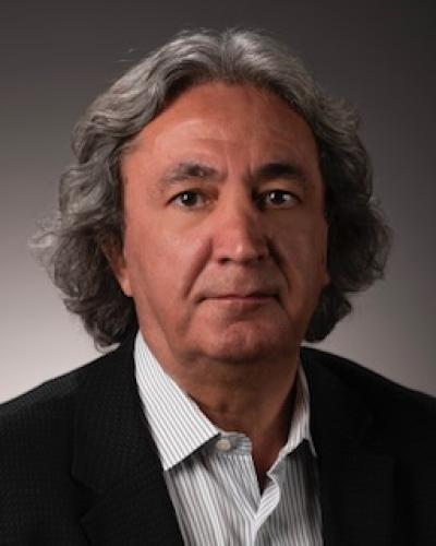 headshot of Cetin Kaya Koc, from the shoulders up, wearing a pin-striped collared shirt and a black blazer