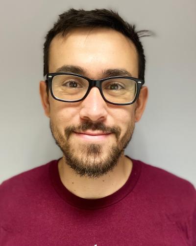 headshot of Fabio Pagani from the shoulders up, wearing a read shirt and black rimmed glasses, smiling