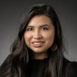 headshot of Jasmine Moreno, from the shoulders up, wearing a black high collared shirt and gold earrings